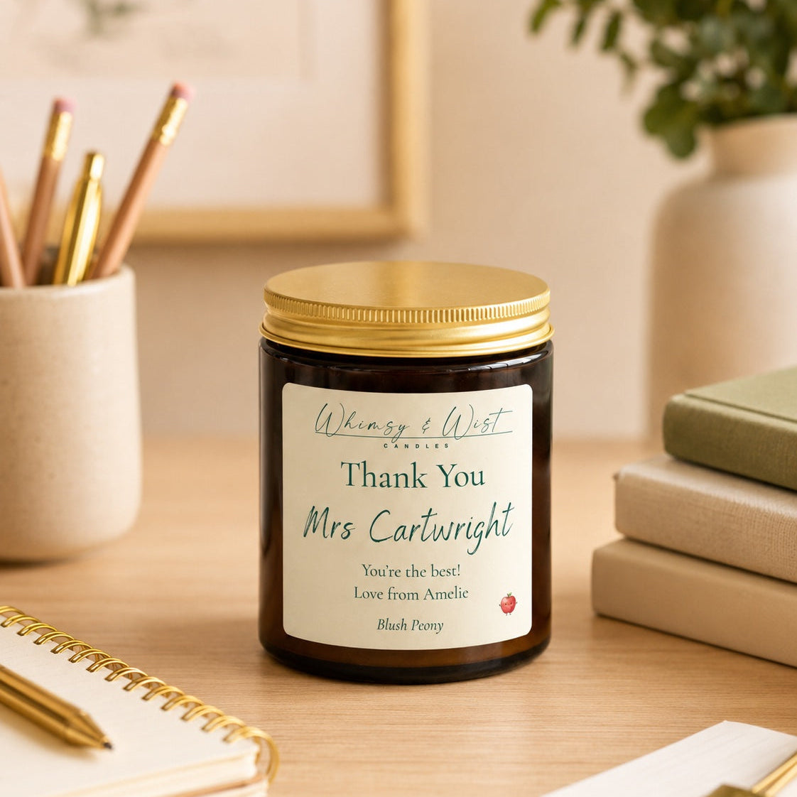 Candle with a personalised label on a desk with stationery items