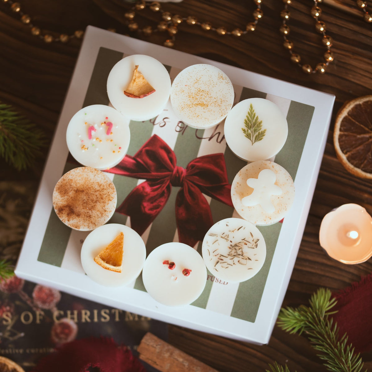 Nine Christmas wax melts arranged on the 'Scents of Christmas' gift box lid with its red velvet bow