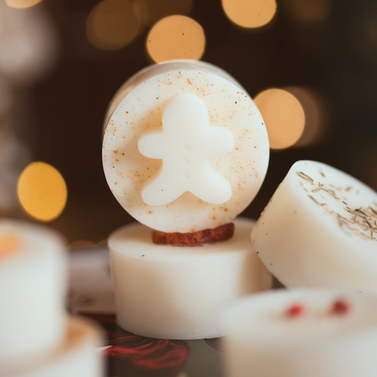 Close-up of a festive wax melt topped with a little gingerbread man, with fairy lights behind