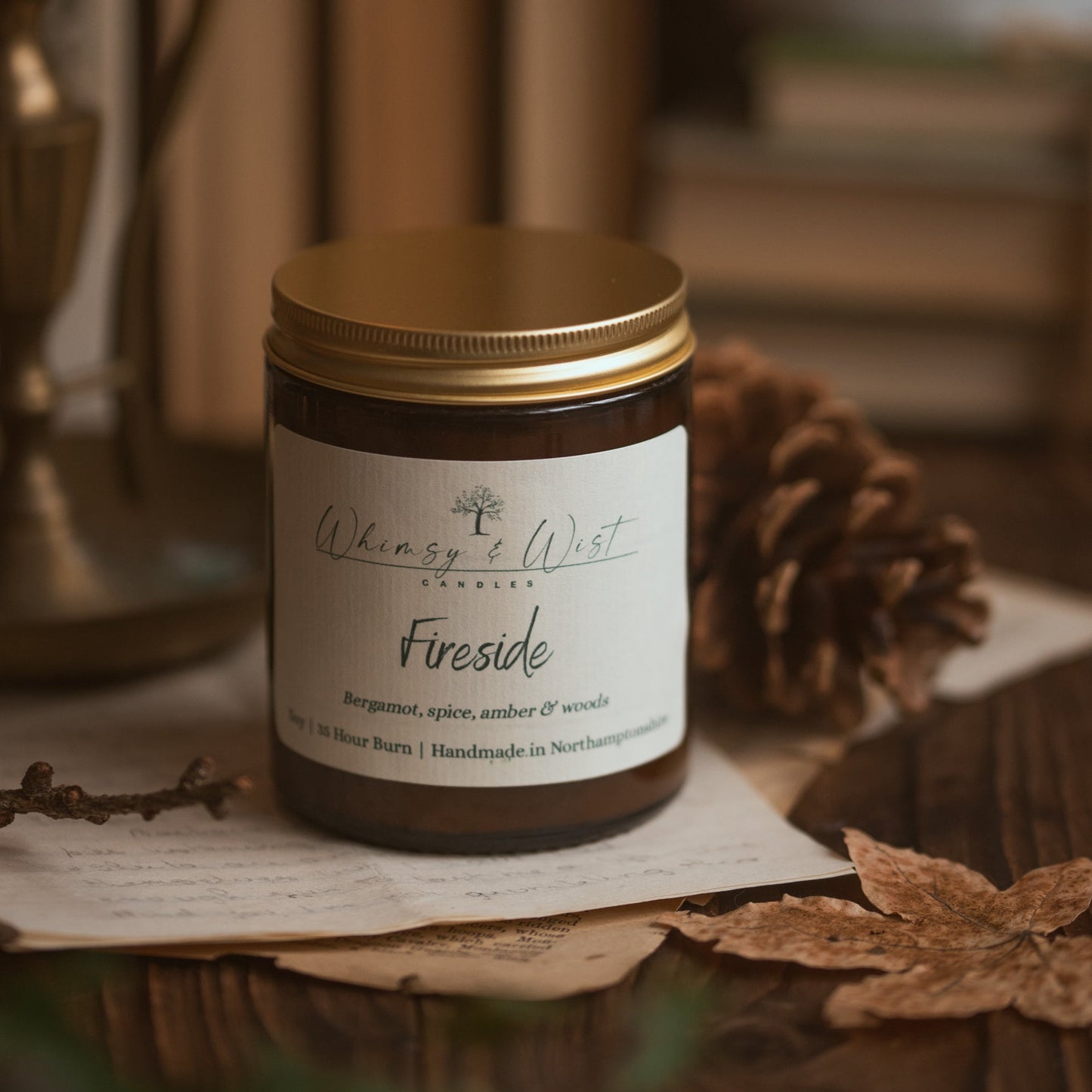 Candle,  labelled Fireside by Whimsy & Wist Candles, against autumnal background