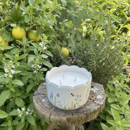 Garden candle in a painted plant pot on a wooden stand with herbs and citrus fruits in the background