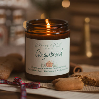 Lit Gingerbread soy candle in an amber jar with gingerbread biscuits and a tartan ribbon