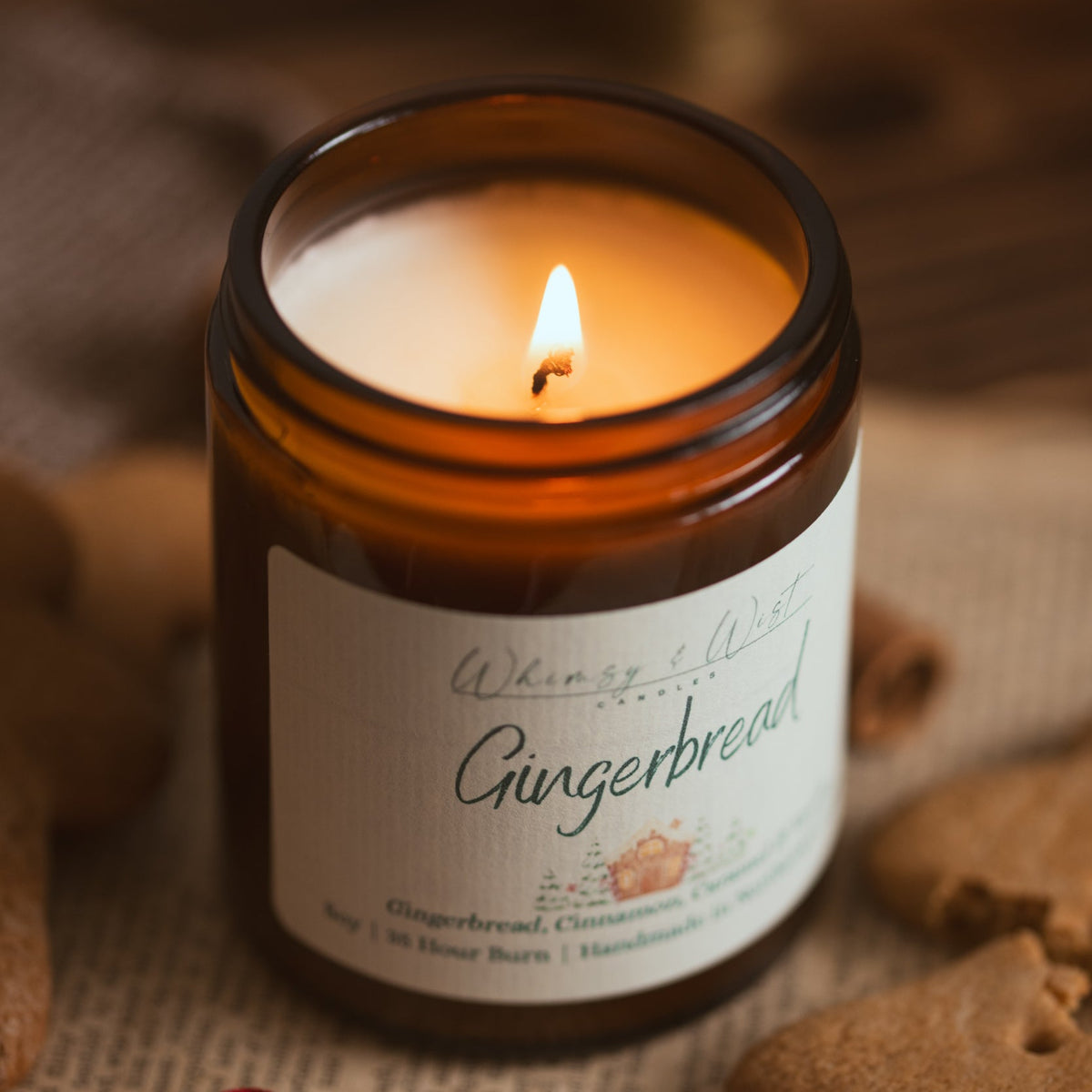 Close-up of a lit Gingerbread soy candle showing the melted wax pool, with gingerbread biscuits around it