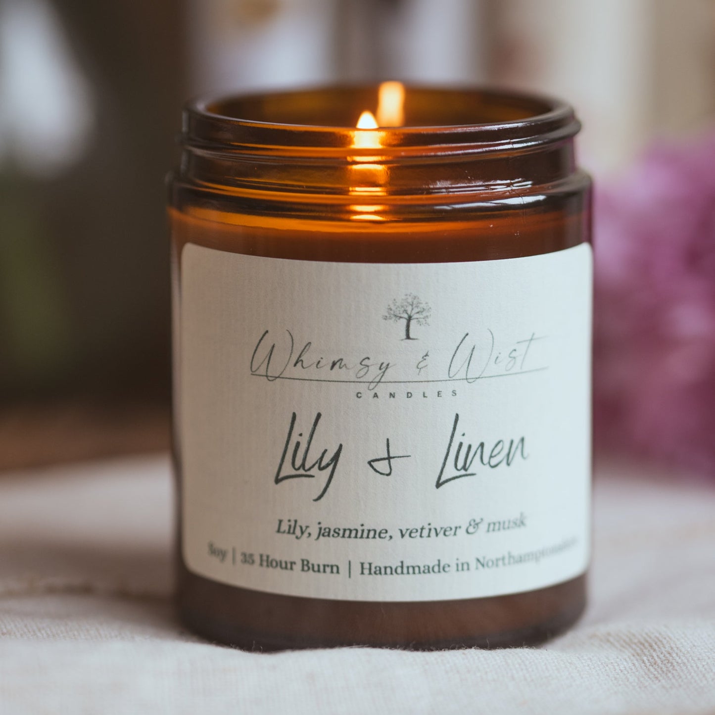 Lily & Linen soy wax candle burning in soft natural spring light