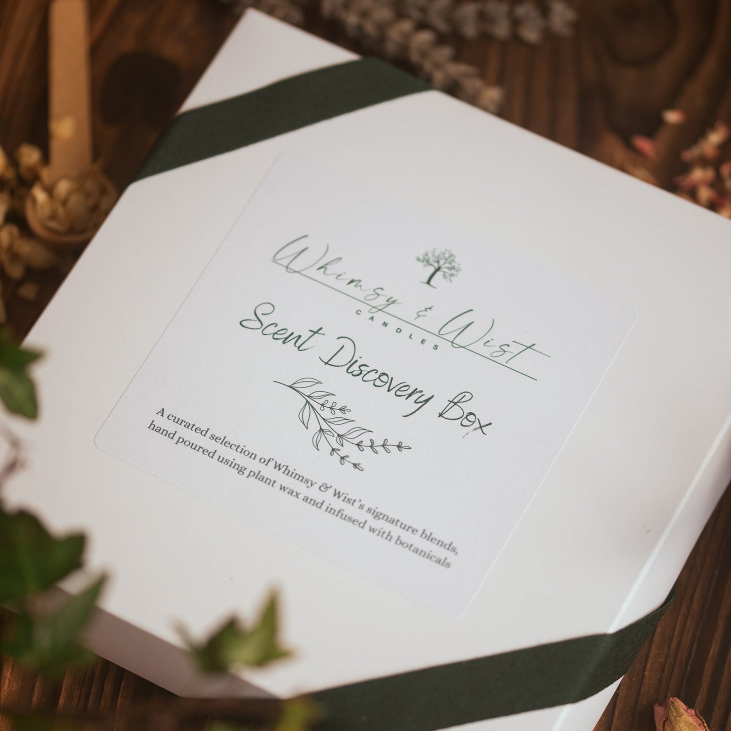 White scent discovery box with green ribbon on a wooden surface