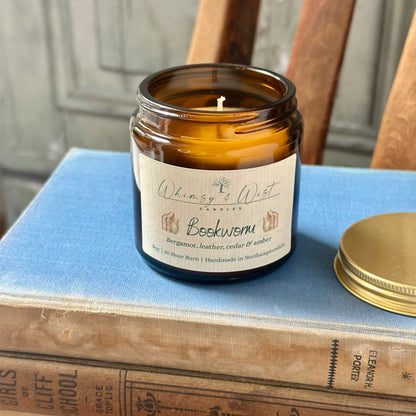 Bookworm soy candle in amber apothecary jar with gold lid, handmade in the UK.