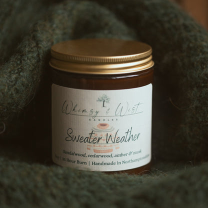 Jar of 'Sweater Weather' candle on a textured green surface