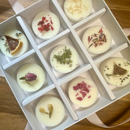 Box of small round wax melts with natural elements on a wooden surface