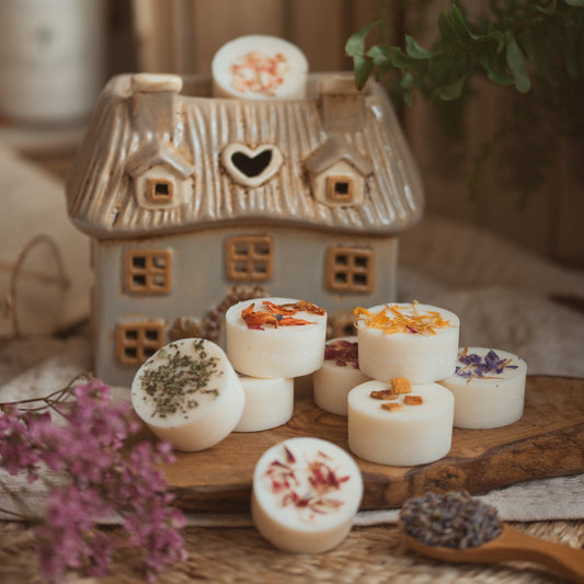 Stoneware thatched cottage wax melt burner with an assortment of wax melts.