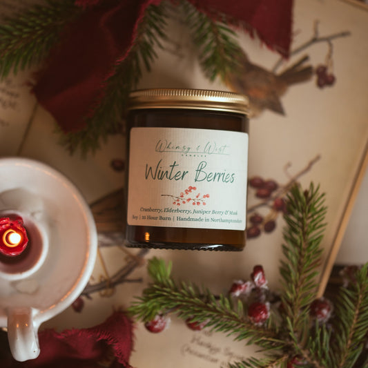Whimsy & Wist Winter Berries soy candle with gold lid, with pine, red berries and a white candle holder