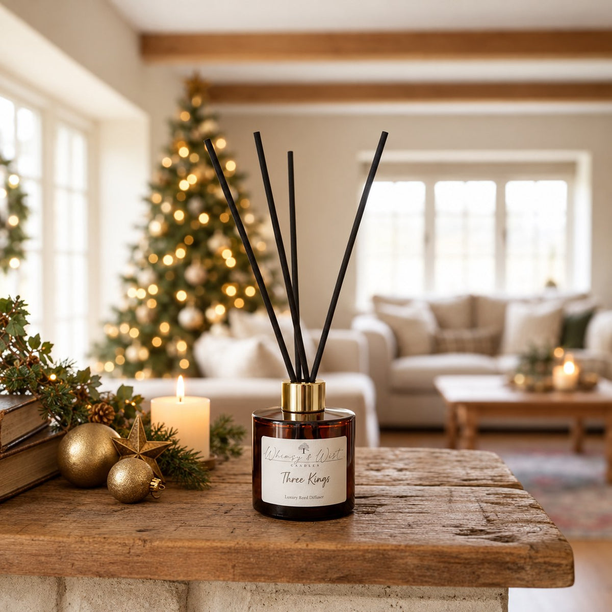 Whimsy & Wist Three Kings reed diffuser on a rustic table with gold baubles, a brass star and a lit candle