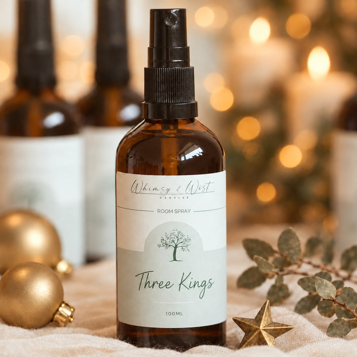 Whimsy & Wist Three Kings 100ml room spray in an amber glass bottle with gold baubles, a brass star and eucalyptus